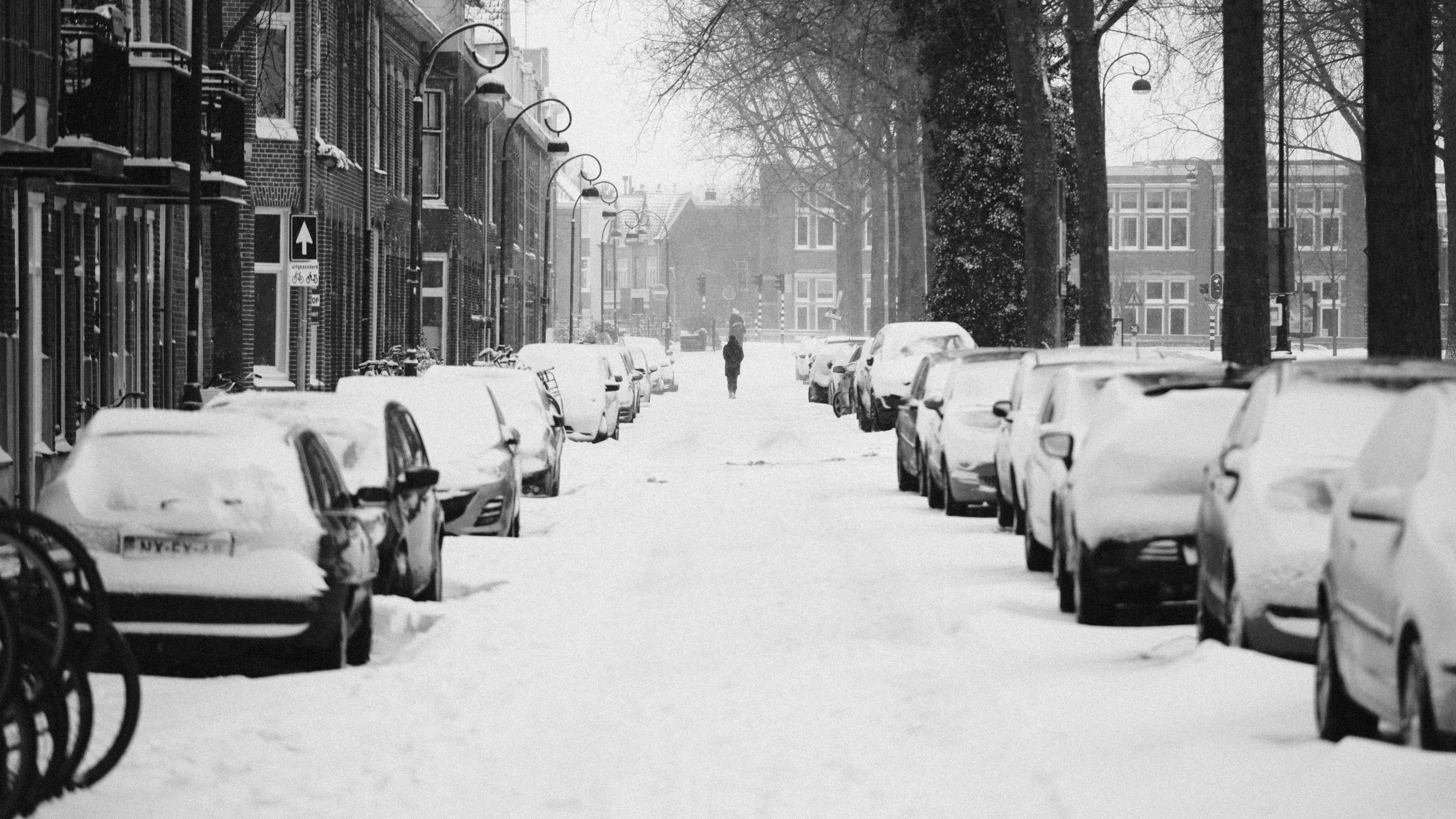 A snow-covered city street with a single figure in the distance.